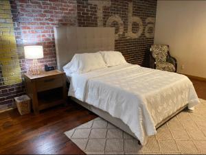 ein Schlafzimmer mit einem Bett und einer Ziegelwand in der Unterkunft The Loft at Bite Me BBQ in Wichita