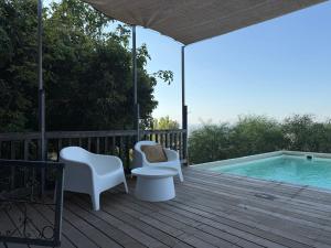 a deck with chairs and a swimming pool at wooden Edge Of The Village in Ma'ale Gamla