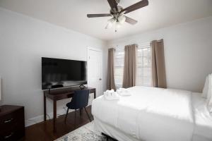 a white bedroom with a bed and a desk and a television at 21st Ave Bham Bungalow in Homewood