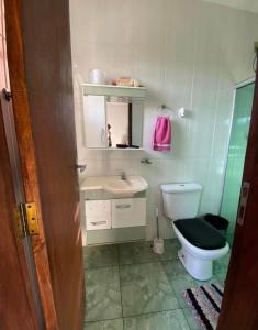 a bathroom with a toilet and a sink and a mirror at Duplex familiar in Contagem