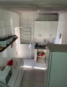 a small kitchen with white cabinets and a refrigerator at Duplex familiar in Contagem