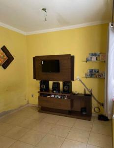 a living room with a tv on a yellow wall at Duplex familiar in Contagem