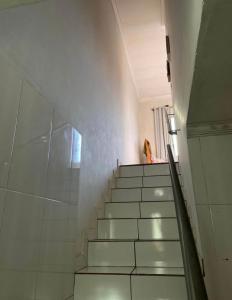 a staircase with white tiles and a person in a window at Duplex familiar in Contagem