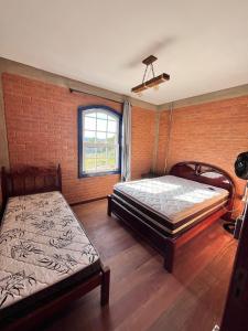 ein Schlafzimmer mit zwei Betten und einer Ziegelwand in der Unterkunft Chalé em Conceição do Ibitipoca in Lima Duarte