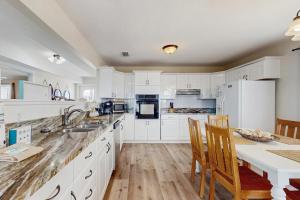 a kitchen with white cabinets and a table with chairs at Malibu Beach House in Dauphin Island