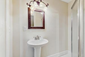 a white bathroom with a sink and a mirror at Malibu Beach House in Dauphin Island +23 photos