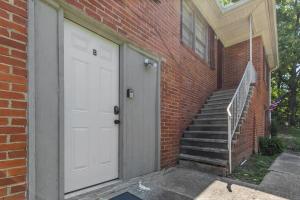 a brick building with a white door and stairs at Broadmoor Bungalow - Unit B in Center Point