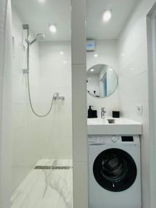 a white bathroom with a washing machine and a sink at White Apartment in Liepāja