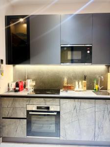 a kitchen with stainless steel appliances and black cabinets at A Tranquil Studio in Airport Residential with Pool - The Essence in Accra