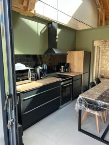 a kitchen with black appliances and a table in a room at La Ruche Enchantée in Champigny-sur-Veude
