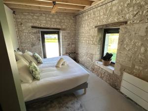 a bedroom with a bed and two windows in it at La Ruche Enchantée in Champigny-sur-Veude