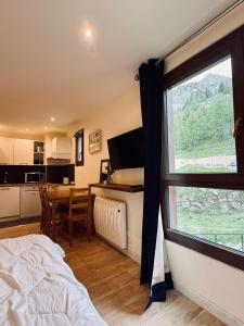 ein Schlafzimmer mit Bett und eine Küche mit Fenster in der Unterkunft Coquet studio au cœur d’Isola 2000 in Isola