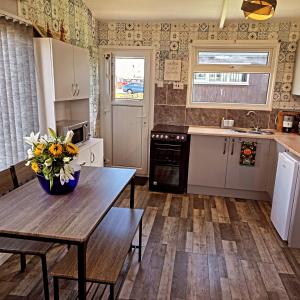 a kitchen with a table with flowers on it at Sherman The Chalet in Withernsea +5 photos