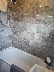 a bath tub in a bathroom with a tile wall at Sherman The Chalet in Withernsea