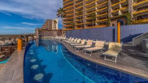 a swimming pool with lounge chairs and a building at Sonoran Sky in Puerto Peñasco