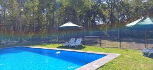 a swimming pool with two umbrellas and two chairs at Cabaña pilina in Pucón +4 photos