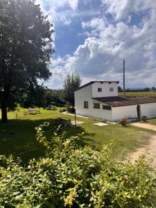 a white house in a field with a tree at B&B Orto di Borghi in Faenza