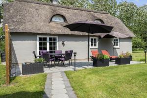 a house with a table and chairs and an umbrella at 10752-Ulfborg-Graevlingevej-14 in Øhuse