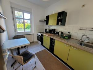 a kitchen with yellow and green cabinets and a table at Carl-Schmäcke-Straße 7 in Neuenhagen