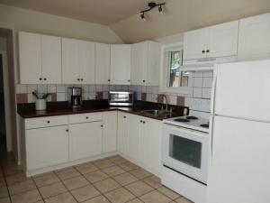 a kitchen with white cabinets and white appliances at Beach front cabin near Nelson, BC in Nelson