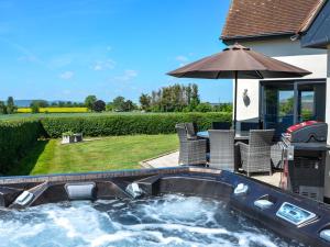 a hot tub in a backyard with chairs and an umbrella at 5 Bed in Madley 78646 in Madley