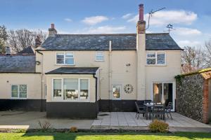 une maison avec une table et des chaises devant dans l'établissement Victoria Cottage - Wensum Retreats, à Gunthorpe