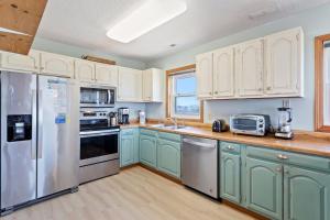 a kitchen with mint green cabinets and stainless steel appliances at 5237 - Carpe Dune in Croatan Shores