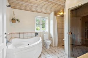 a bathroom with a white tub and a toilet at 20795-Ulfborg-Fyrrebakken-6 in Sundhuse +18 photos
