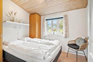 a bedroom with a bed and a chair and a window at 20795-Ulfborg-Fyrrebakken-6 in Sundhuse