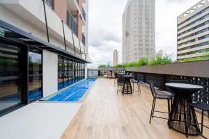 a balcony with tables and chairs on a building at Estúdio Moderno e Completo no Coração de Curitiba in Curitiba