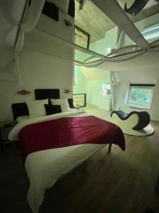 une chambre avec un grand lit avec une couverture rouge et blanche dans l'établissement La Maison Du Plaisir Loveroom Pontorson, à Pontorson