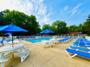 a pool with blue umbrellas and white chairs and tables at Island Club #111 in Put-in-Bay