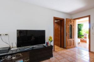Una sala de estar con un televisor de pantalla plana grande. en 2BR Ground-Floor Villa Apartment with Pool, 10mins drive to Ibiza Airport, en Sant Josep de sa Talaia