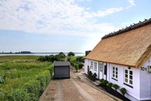 a white cottage with a thatched roof in a field at 11844-Nykobing-Sj-Egebjergvej-101 in Nygård
