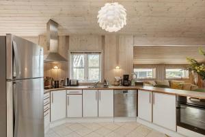 a kitchen with white cabinets and a stainless steel refrigerator at L35-Rodby-Tjornevaenget-7 in Rødby +15 photos
