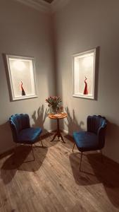 two chairs and a table in a room with two windows at Angiolina Suite in Naples