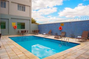 a swimming pool with chairs and a brick wall at Hotel Dan Inn Express Ribeirão Preto By Nacional Inn in Ribeirão Preto