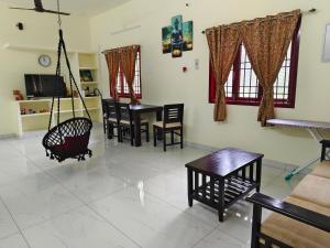 a living room with tables and chairs and a swing at Ecstasy Homestay Puducherry in Pondicherry