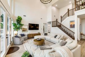 a living room with white furniture and a staircase at Dock and Hot Tub! High-End Cedar Creek Lake Retreat in Gun Barrel City