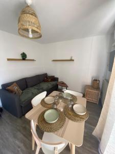 ein Wohnzimmer mit einem Tisch und einem Sofa in der Unterkunft L' instant Bohème T2 clim , piscine , parking in Balaruc-les-Bains