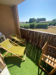2 Stühle auf einem Balkon mit einem Zaun in der Unterkunft L' instant Bohème T2 clim , piscine , parking in Balaruc-les-Bains