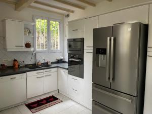 a kitchen with a stainless steel refrigerator and white cabinets at Belle villa de charme avec piscine in Tourrettes