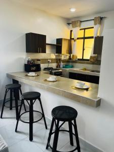 a kitchen with three bar stools and a counter at Ntates Place Diani Beach in Diani Beach