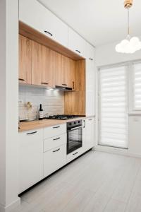 a white kitchen with wooden cabinets and a window at NeoLoft 1st in Popeşti-Leordeni