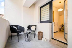 a balcony with two chairs and a table and a window at NeoLoft 1st in Popeşti-Leordeni