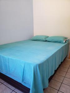 a bed in a room with a blue blanket on it at Casa Pequena e agradável em Ilhéus in Ilhéus