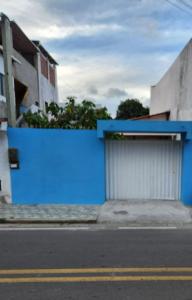 a blue wall next to a building with a garage at Casa Pequena e agradável em Ilhéus in Ilhéus