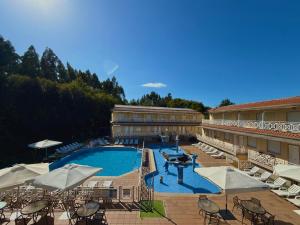 a large swimming pool with chairs and umbrellas next to a building at Sun Galicia Hotel y Apartamentos in Sanxenxo +34 photos