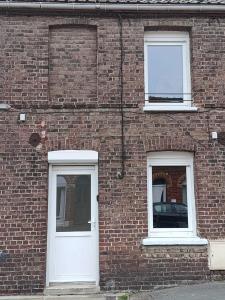 un edificio in mattoni con due porte bianche e due finestre di Charmante maisonnette a Saint-Amand-les-Eaux