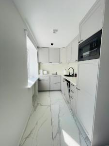 a white kitchen with marble floors and white cabinets at White Apartment in Liepāja +16 photos